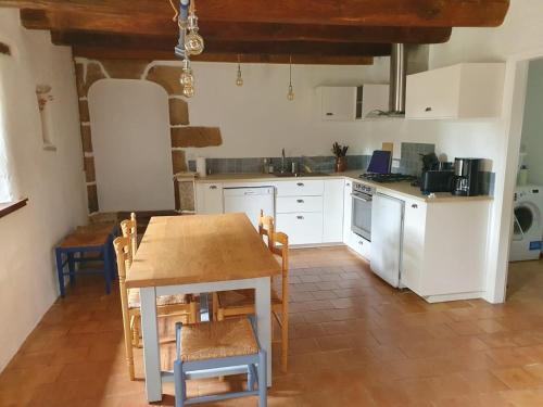 une cuisine avec des armoires blanches et une table et des chaises dans l'établissement Charming Breton farmhouse, à Rédené