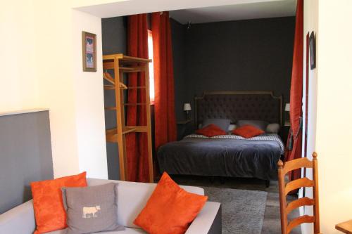 a bedroom with a bed and a couch with orange pillows at L'écurie de Vieux-Moulin in Vieux-Moulin