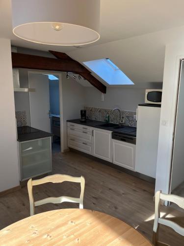 une cuisine avec une table et un plafond avec une lucarne dans l'établissement 2 pièces neuf, au coeur de ville 37m2, au Creusot