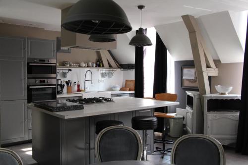 a kitchen with a large island with chairs in it at L'écurie de Vieux-Moulin in Vieux-Moulin