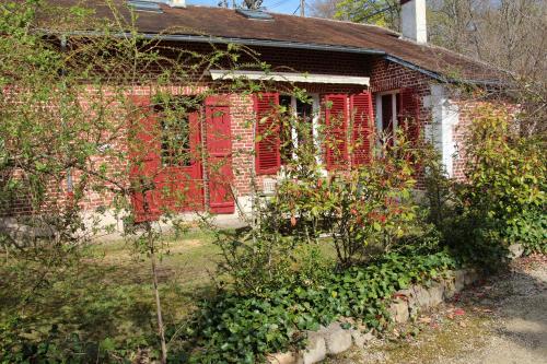 an old brick house with red shutters and flowers at L'écurie de Vieux-Moulin in Vieux-Moulin