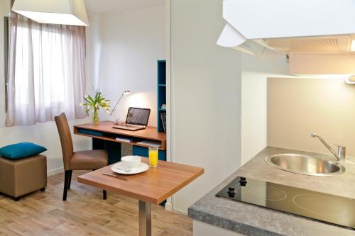une cuisine avec une table et un bureau avec un ordinateur portable dans l'établissement Odalys City Amiens Blamont, à Amiens