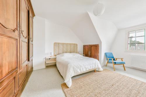 - une chambre blanche avec un lit et une chaise bleue dans l'établissement Maison pour 8 avec jardin, 300 m de la mer, à Saint-Gildas-de-Rhuys