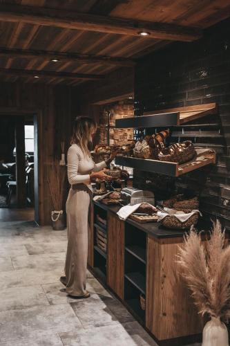 a woman standing in a kitchen preparing food at Jufenalm BOHO & Wellnesshotel in Maria Alm am Steinernen Meer