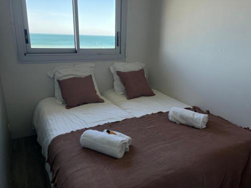 - 2 lits dans une chambre avec 2 oreillers et une fenêtre dans l'établissement Appartement T2 vue mer, à Cabourg