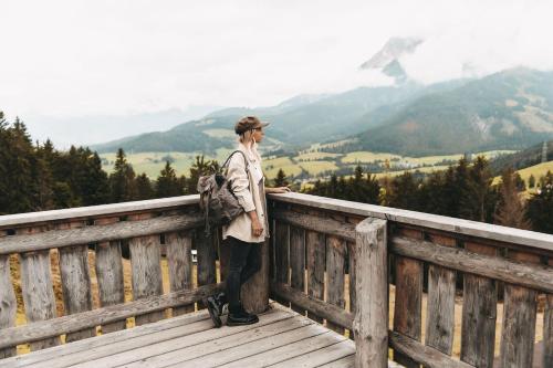 a man standing on a bridge looking at the mountains at Jufenalm BOHO & Wellnesshotel in Maria Alm am Steinernen Meer