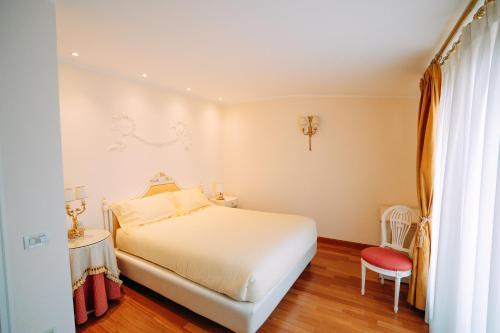 a bedroom with a white bed and a red chair at Suite Romantic vista Lago in Stresa