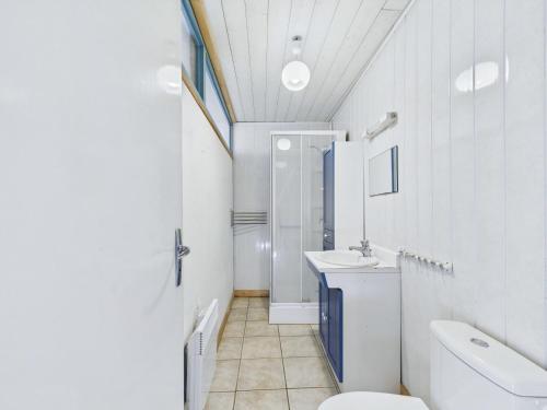 une salle de bain blanche avec un lavabo et des toilettes dans l'établissement À 400m de la plage, charmante maison pour 7, à Plouguerneau