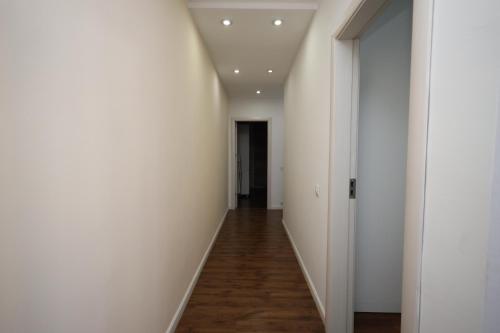 an empty hallway with white walls and wood floors at Dodona ApartHotel in Prishtina in Pristina