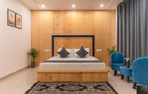a bedroom with a bed and two blue chairs at The Cloudberry Kasauli I Guaranteed Best Price I Serviced Villa I Open Air Rooftop I Couple Friendly I Pvt Balcony I Kasauli By ExoticStays in Kasauli