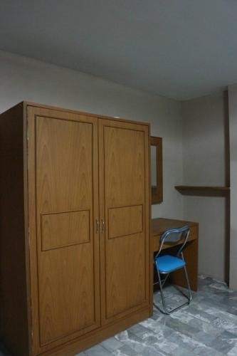 a room with a wooden cabinet and a blue chair at อารมย์ดี อพาทเม้นท์ ขอนแก่น in Ban Nong Waeng