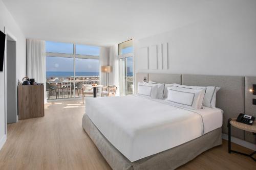 a white bedroom with a large bed and a balcony at Meliá Lloret de Mar in Lloret de Mar