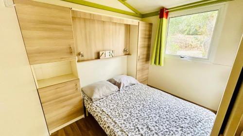 una piccola camera da letto con un letto e una finestra di Chalet M tout confort proche des plages a Pianottoli-Caldarello