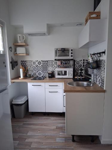 une petite cuisine avec des armoires blanches et un évier dans l'établissement Grand Studio Mezzanine au calme dans l'hypercentre, à Rochefort