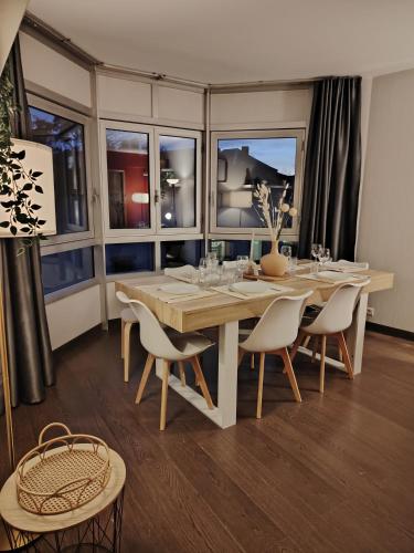 une salle à manger avec une table, des chaises et des fenêtres dans l'établissement Appartement plein centre ville, chaleureux et spacieux, à Cholet