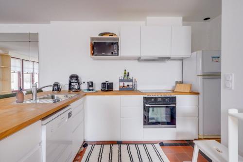 une cuisine blanche avec un évier et une cuisinière dans l'établissement Centre du Moulleau -Apt Voile au Vent- 5 minutes à pied de la plage, à Arcachon