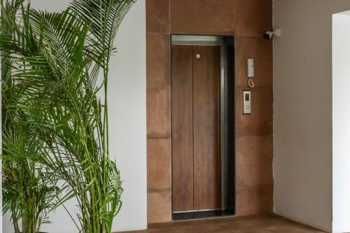 a hallway with a wooden door and a plant at Casa De Solares- New 2BHK Apartment with Pool Candolim in Pilerne