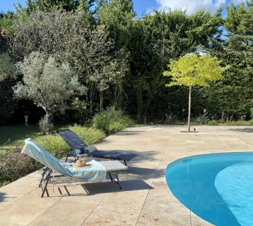 une chaise assise à côté d'une piscine dans l'établissement Mas du Micocoulier, à Paradou