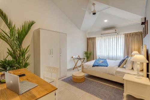 a bedroom with a bed and a laptop on a desk at Casa De Solares- New 2BHK Apartment with Pool Candolim in Pilerne