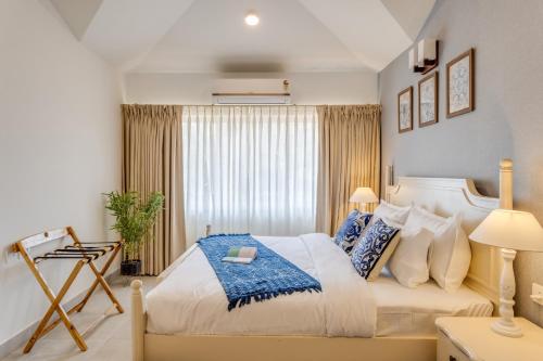 a bedroom with a large bed with blue and white pillows at Casa De Solares- New 2BHK Apartment with Pool Candolim in Pilerne