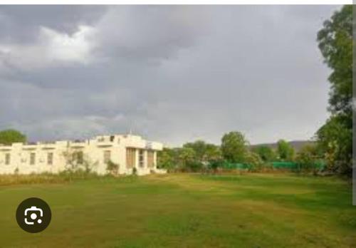 a large white building in a grassy field at Ranthambore Bagh niwas in Khilchipur