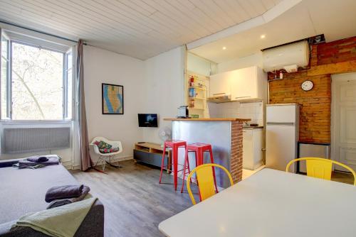 Il comprend une cuisine équipée d'un réfrigérateur, d'une table et de chaises. dans l'établissement Le petit Strasbourg hypercentre, à Toulouse