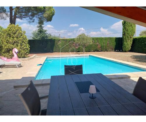 a swimming pool with a wooden table and a table sidx sidx sidx at Le Mas Valou, villa en pierre dans les hauteurs de Fayence in Tourrettes
