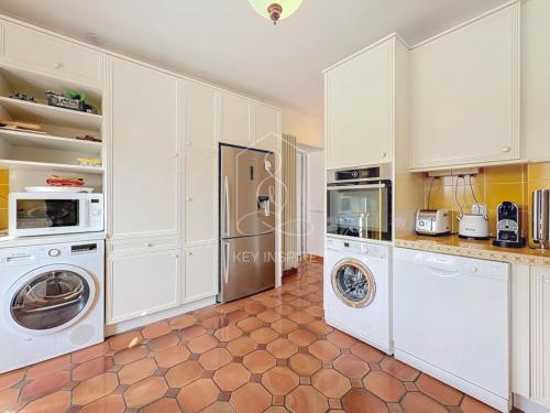 a kitchen with white cabinets and a washer and dryer at Le Mas Valou, villa en pierre dans les hauteurs de Fayence in Tourrettes