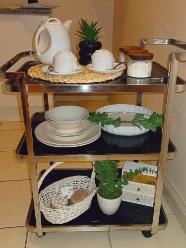 a shelf with dishes and a tea pot and a plant at Matria Nest in East London