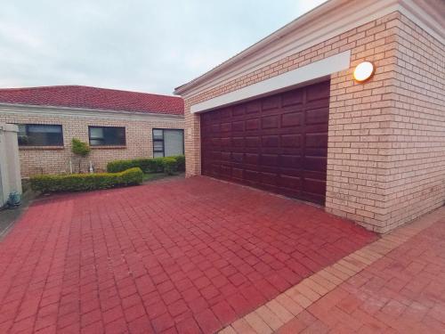 a brick garage with a red garage door at Sugarbird Nest in East London