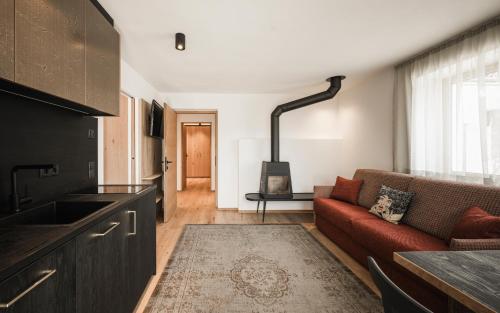 a living room with a red couch and a kitchen at Pension Haus Tirol in Laion
