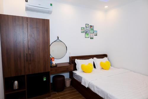 a bedroom with a bed with yellow pillows and a mirror at Suka Hotel in Tây Ninh