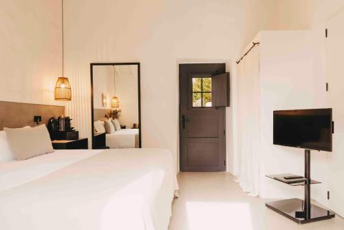 a white bedroom with a bed and a television at Finca Serena Mallorca, Small Luxury Hotels in Montuiri