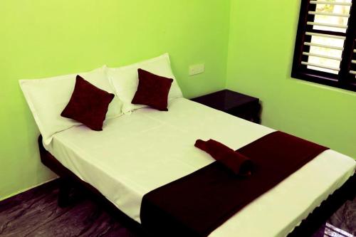 Green Wayanad Homestay في Batheri: سرير في غرفة خضراء وعليها وسادتين