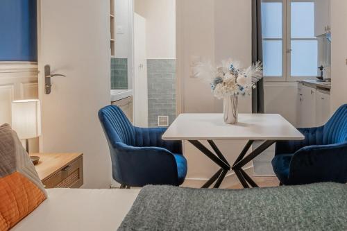 une table avec deux chaises bleues et un vase avec des fleurs dans l'établissement Studio Douillet pour 2 au Cœur de Montmartre-II, à Paris