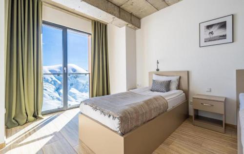 a bedroom with a bed and a large window at New Gudauri Four season in Gudauri