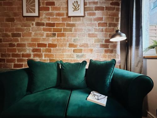 zieloną kanapę w pokoju z ceglaną ścianą w obiekcie Apartament Egzotyczny w Toruniu