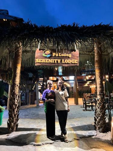 two women standing under a sign at a resort at Pu Luong Serenity Lodge in Pu Luong