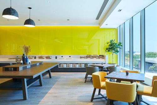 a restaurant with yellow walls and tables and chairs at Holiday Inn Express Melbourne Southbank by IHG in Melbourne