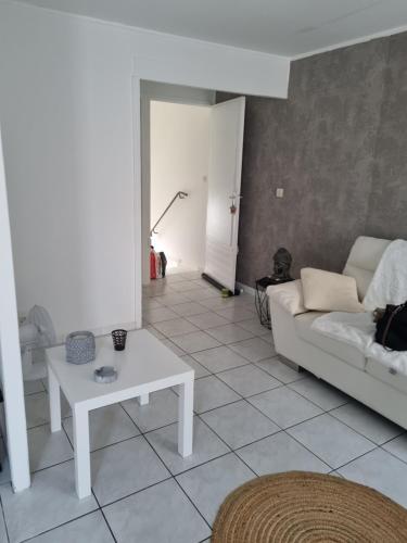 un salon avec un canapé blanc et une table dans l'établissement Location saisonnière, à Agde