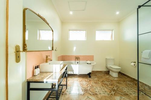a bathroom with a tub and a sink and a toilet at The Victorian Manor in Victoria Falls