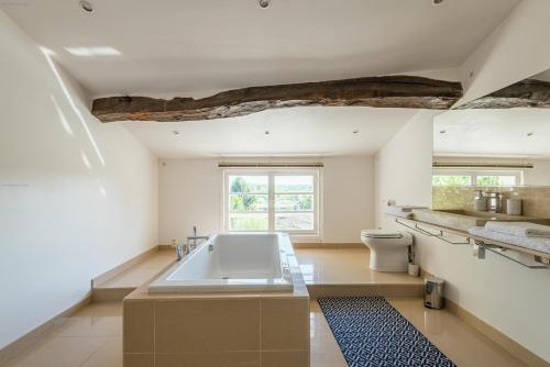 une salle de bain avec une grande baignoire dans une chambre dans l'établissement Demeure en pierre au cœur des vignobles de Bordeaux, à Saint-Germain-de-la-Rivière