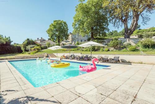- une piscine avec des flamants gonflables et des personnes y séjournant dans l'établissement Demeure en pierre au cœur des vignobles de Bordeaux, à Saint-Germain-de-la-Rivière