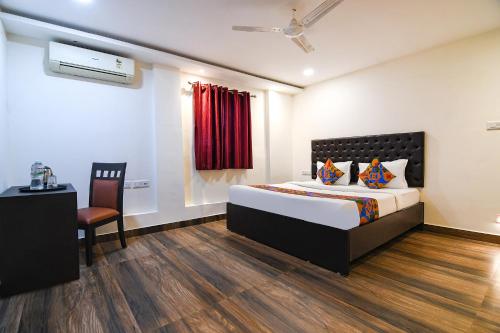 a bedroom with a bed and a chair and a window at FabHotel KGF in Kolkata