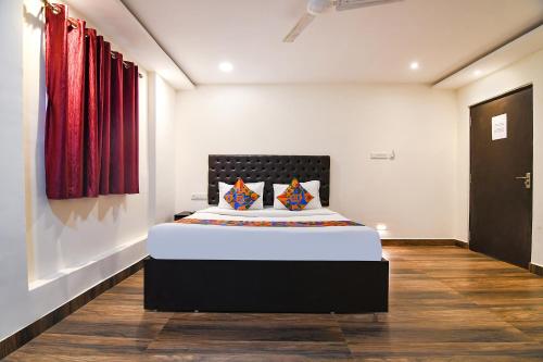 a bedroom with a large bed with red curtains at FabHotel KGF in Kolkata