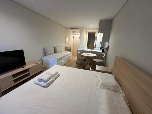 a bedroom with a white bed and a living room at New Douro 403 with parking in Vila Nova de Gaia