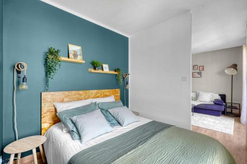 une chambre avec un lit avec un mur bleu dans l'établissement Spacious Apartment Blagnac Parking-Tram-Airport, à Blagnac