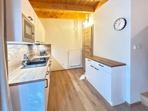 a kitchen with a sink and a clock on the wall at Domek na Vysočině in Svratouch