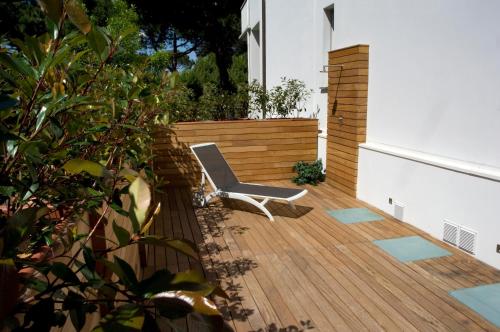 a chair sitting on a wooden deck next to a building at Hotel Eros Residence in Cervia