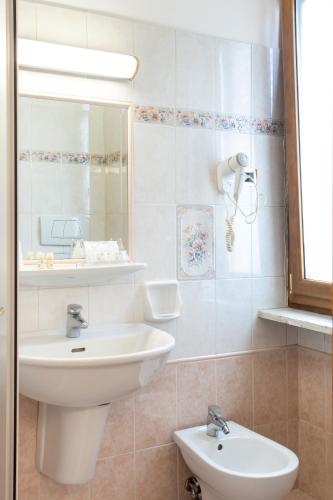 a white bathroom with a sink and a mirror at Hotel Santa Prisca in Rome